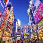 Tokyo, Japan - August 1, 2015: Crowds pass below colorful signs in Akihabara. The well known electronics district specializes in the sales of video games, anime, manga, and computer goods.