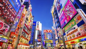 Tokyo, Japan - August 1, 2015: Crowds pass below colorful signs in Akihabara. The well known electronics district specializes in the sales of video games, anime, manga, and computer goods.