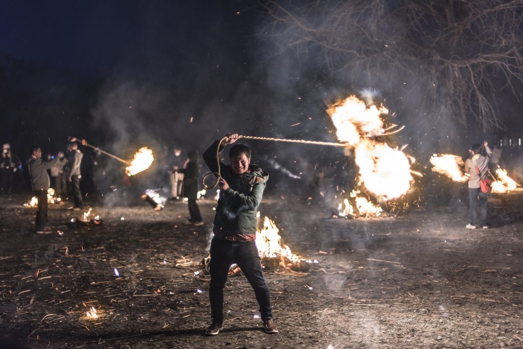 Aso, Kumamoto, Japan – March 21, 2015: Festivalgoer swinging a flaming bundle of straw at the Aso Shrine Fire Festival, Japan