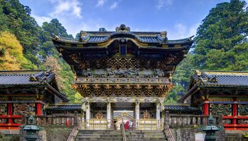 Nikko, Japan - November 1, 2012: A shinto priest sweeps under the Yomeimon gate at Tosho-gu Shrine. Founded in 1617, the remains of the first shogun Tokugawa Ieyasu are entombed here.