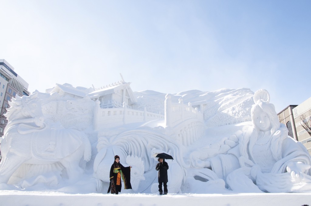 Performers stand in front of a giant snow sculpture at the Sapporo snow festival